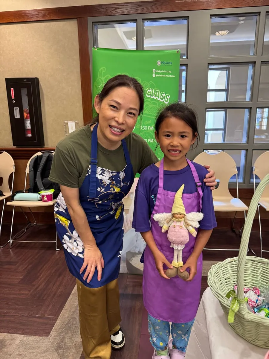 An instructor and a girl in an apron pose at the cooking class.