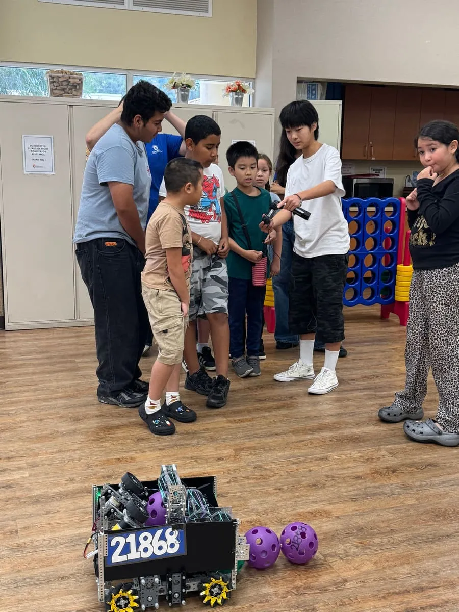 Children crowd around robot 21868 and its purple game balls.