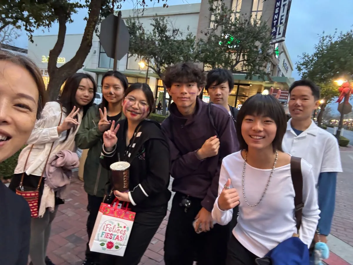 Teen volunteers and a parent take a selfie on an evening street.