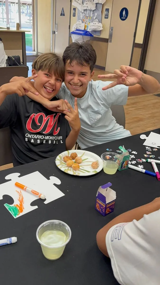 Two boys clown for the camera at a puzzle table.