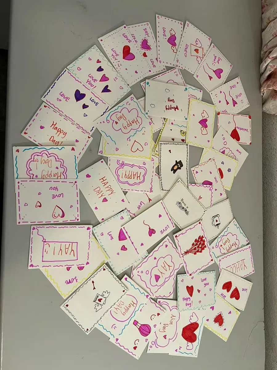 Dozens of handmade valentine cards spread out on a table.