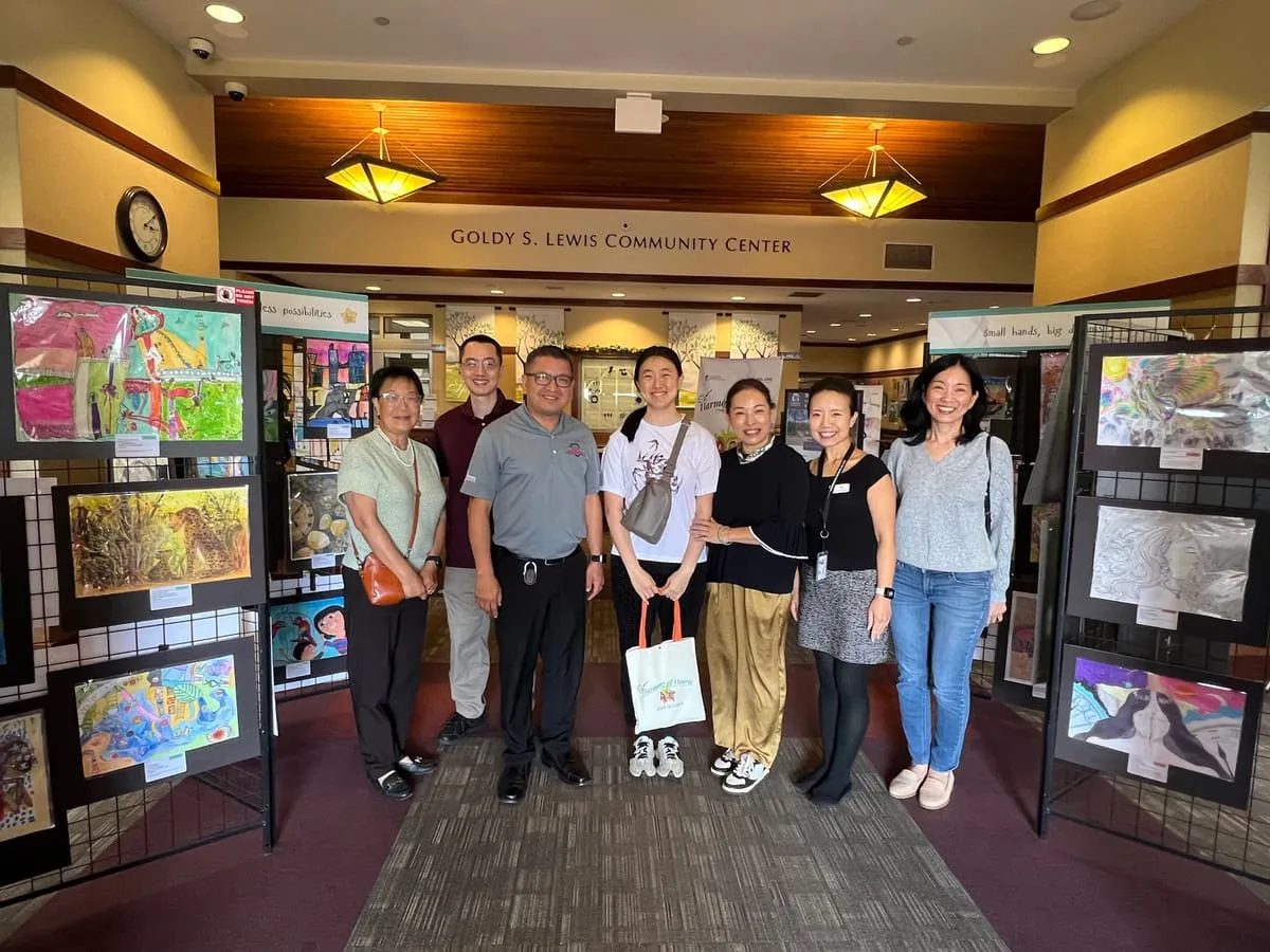 Volunteers and guests stand in front of the exhibition panels at the entrance of the Goldy S. Lewis Community Center.