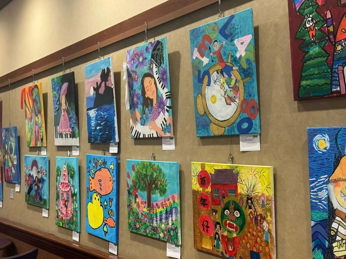 A wall of brightly colored student paintings in two rows.