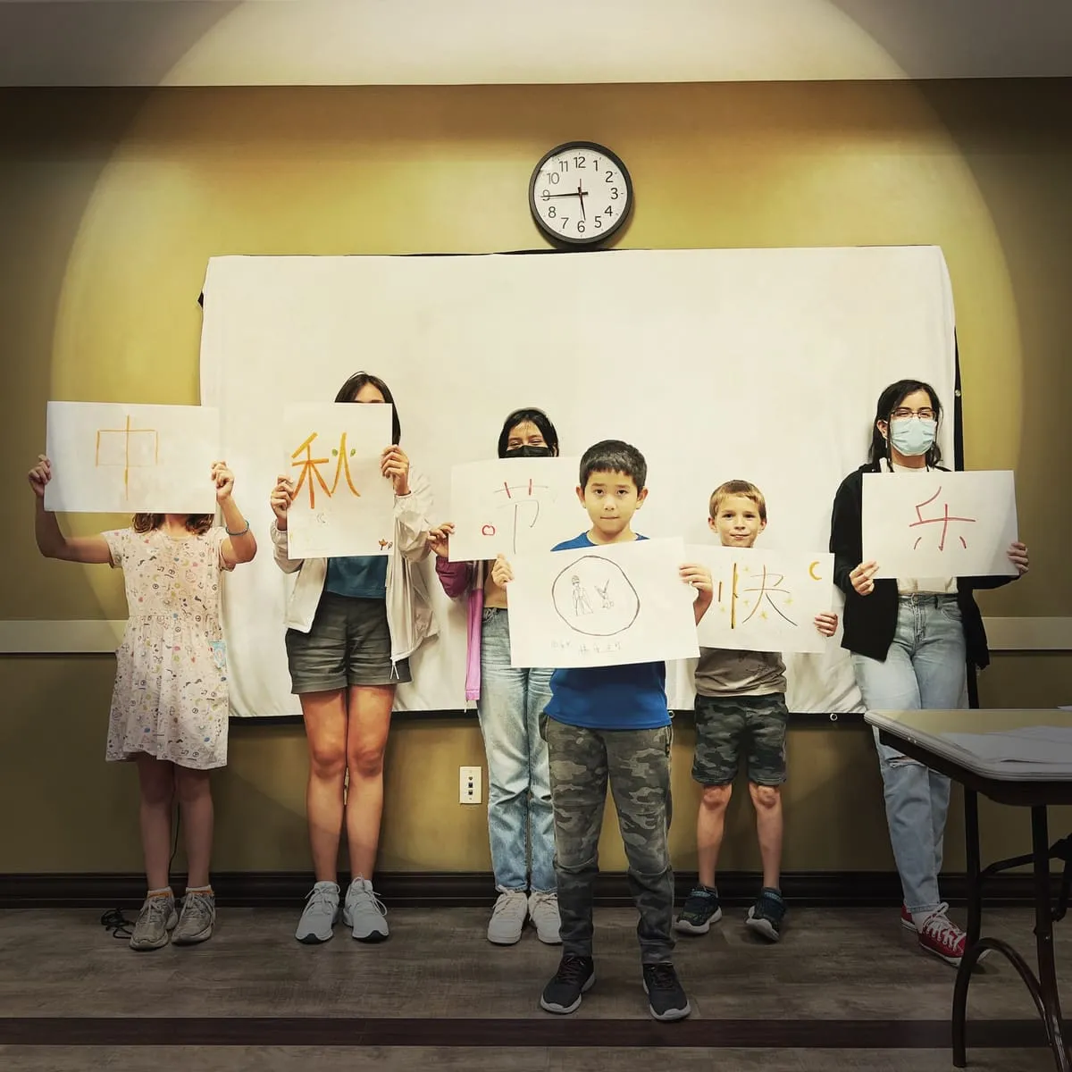 Children hold up Chinese characters they brushed in calligraphy.