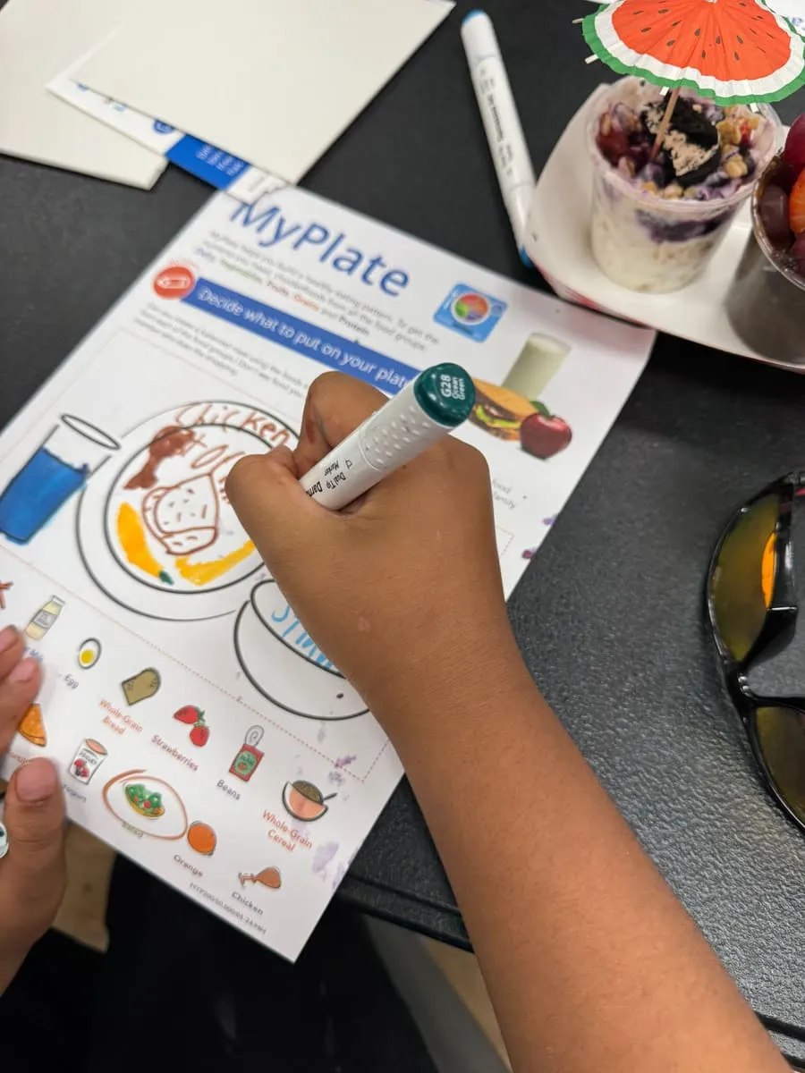A child colors a MyPlate nutrition worksheet.
