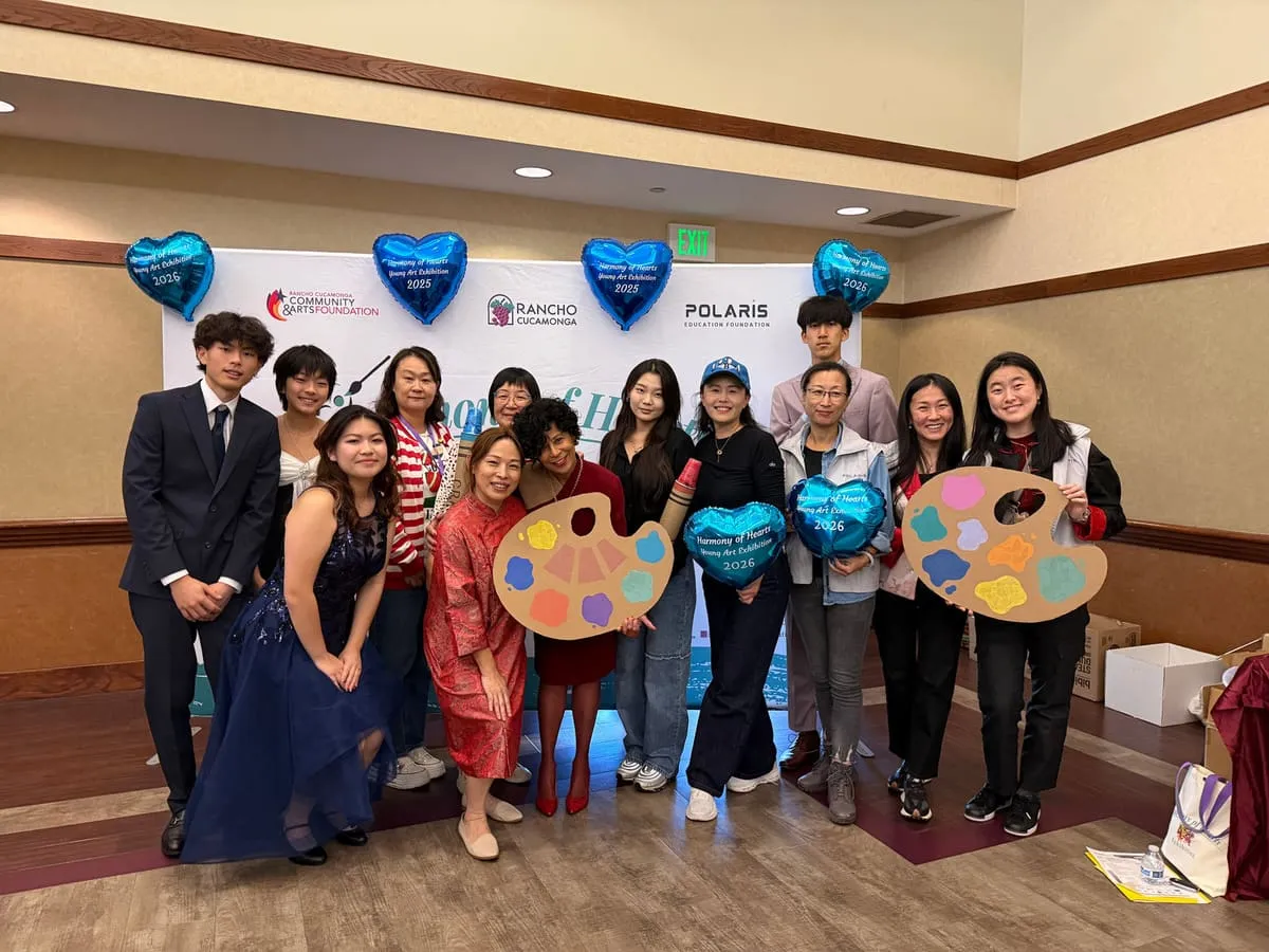 Volunteers and guests hold giant paint-palette props and heart balloons in front of the backdrop.