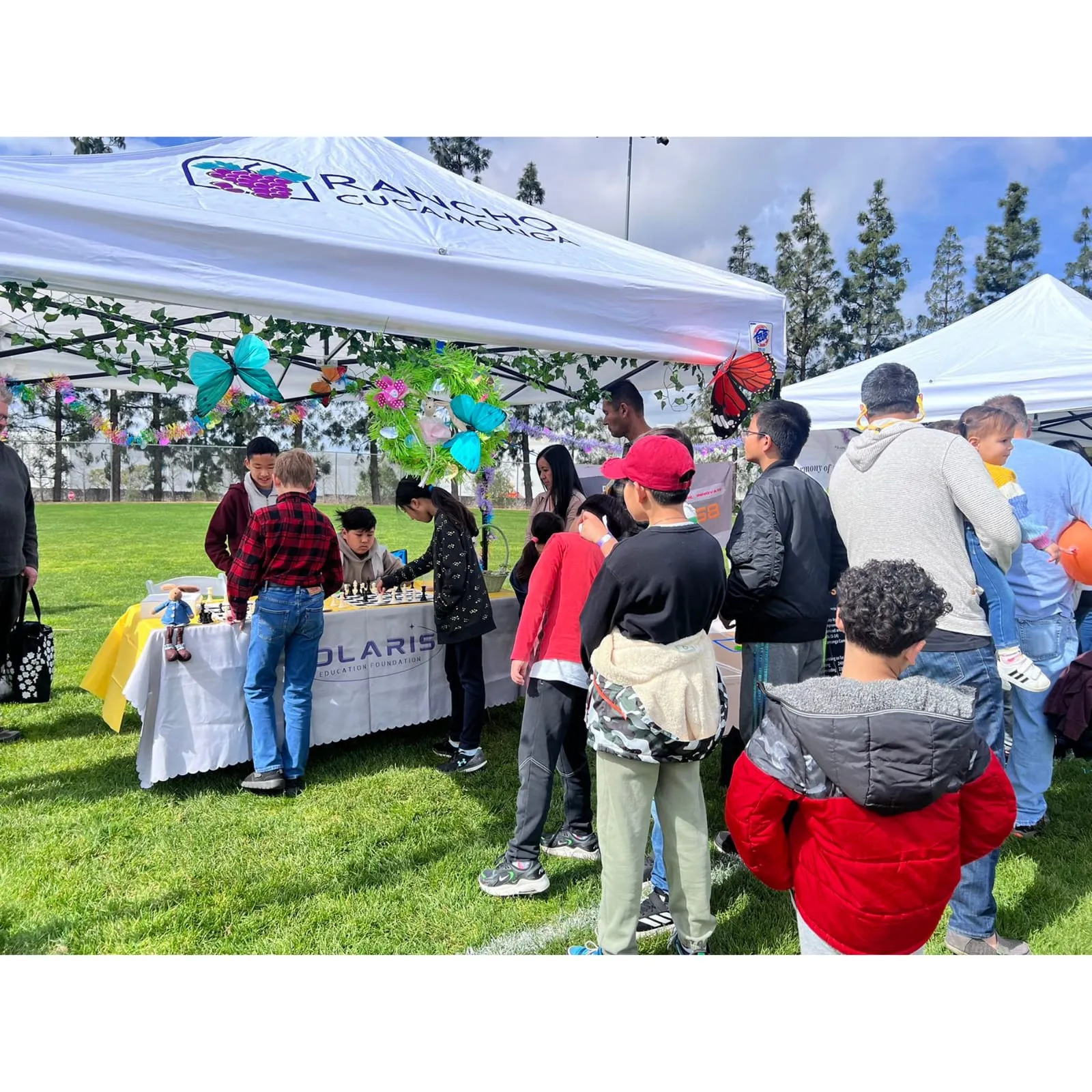 Children and parents crowd around the Polaris booth under festival tents on a sunny lawn.