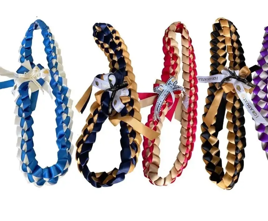 Braided ribbon leis side by side in blue and white, navy and gold, red and gold, black and gold, and purple and silver.